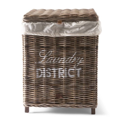 Rattanowy kosz na pranie w odcieniach brązu, z tkaninowym wiekiem. Widoczny napis Laundry District na froncie, wykonany z plecionki o teksturze. Kosz stoi w pionie na krótkich nóżkach, z miękką osłoną wewnętrzną.