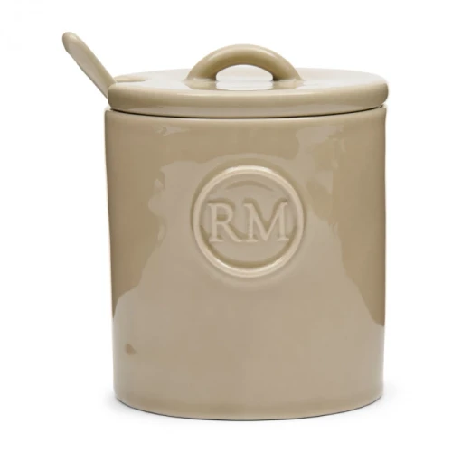 Cukiernica z łyżeczką Portofino w kolorze beżowym, wykonana z ceramiki. Okrągły kształt z wygodnym uchwytem na pokrywce oraz delikatnym logo RM na froncie. Ustawiona na białym tle, w pozycji stojącej, z łyżeczką umieszczoną obok.