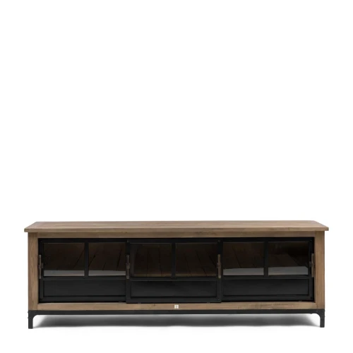 Szafka RTV w stylu loftowym The Hoxton. Wymiary 190x42x45 cm, drewniana, z blatem w odcieniu jasnego brązu. Przeszklone drzwiczki z czarnymi metalowymi ramkami, stojąca na metalowych nóżkach. Proste tło, frontalny kąt ujęcia.