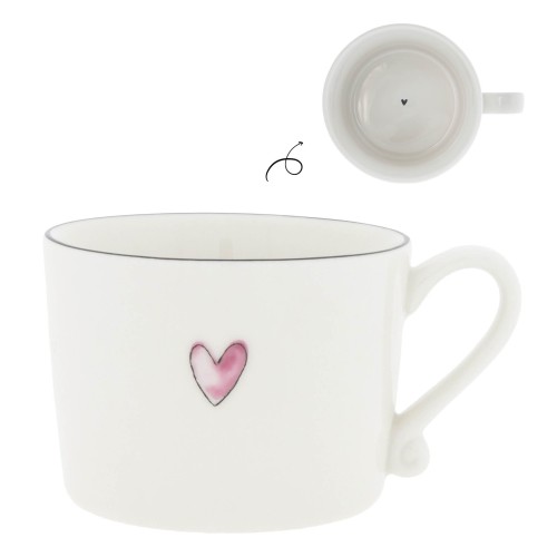 Biały kubek Rose Heart Bastion Collection z różowym sercem, lekko zaokrąglonym brzegiem, minimalistyczną rączką, gładkim wnętrzem i małym czarnym sercem na dnie.