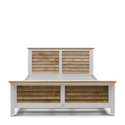 Łóżko w stylu Hamptons z białą ramą i drewnianymi, poziomymi panelami na wezgłowiu oraz przedniej części. Widok frontalny, prezentujące wymiary 180x200 cm. Górna część wykonana z jasnego drewna. Prosta, elegancka forma bez dekoracji.