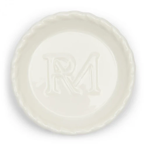 Podstawka Elegant Twist Tea Tip Riviera Maison w kolorze białym, okrągła, z delikatnym brzegiem i wyciętym logo RM na środku. Ujęcie frontalne, z leżącą podstawką na jednolitym tle, pokazujące szczegóły faktury ceramiki.