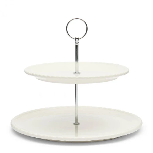 Biała etażerka Elegant Twist Riviera Maison z dwoma poziomymi talerzami, wykonana z ceramiki. Posiada metalowy uchwyt w górnej części. Ujęcie frontalne, produkt stoi na płasko, talerze mają faliste brzegi. Proste tło podkreśla elegancję.