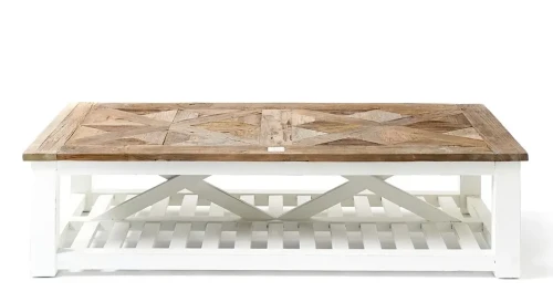 Stolik kawowy w stylu Hamptons, prostokątny, z górnym blatem z jasnego drewna z geometrycznym wzorem, i białą, kratkowaną podstawą. Ujęcie frontalne, produkt w pozycji stojącej na jednolitym tle. Wymiary 150x40x70 cm.