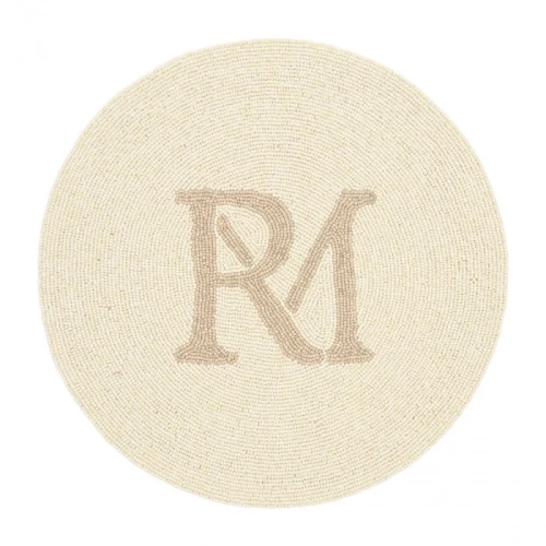 Okrągła podkładka RM Monogram Riviera Maison z naturalnych materiałów, beżowa z jasnobrązowym logo RM, teksturowana powierzchnia, bez dekoracji, na jednolitym tle.