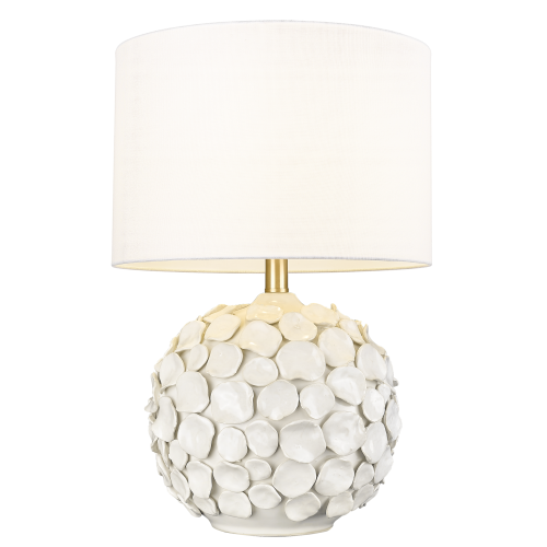 Stylowa Lampa Stołowa Kotor Biała o zaokrąglonej podstawie, pokryta fakturą przypominającą białe kamienie, ze złotym wykończeniem u podstawy. U góry znajduje się jasny, okrągły klosz z materiału. Ujęcie frontalne na stojącej lampie.