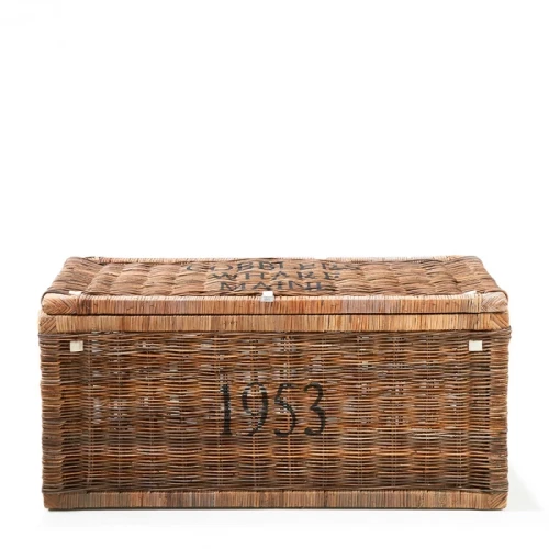 Rattanowy kufer Trunk Cobblers Wharf M Riviera Maison w kolorze naturalnym, z widocznymi zdobieniami i tekstem 1953. Z góry lekko otwarty, prezentuje swoją pojemność. Wykonany z materiału imitującego rattan, o wymiarach 90x40x45 cm.