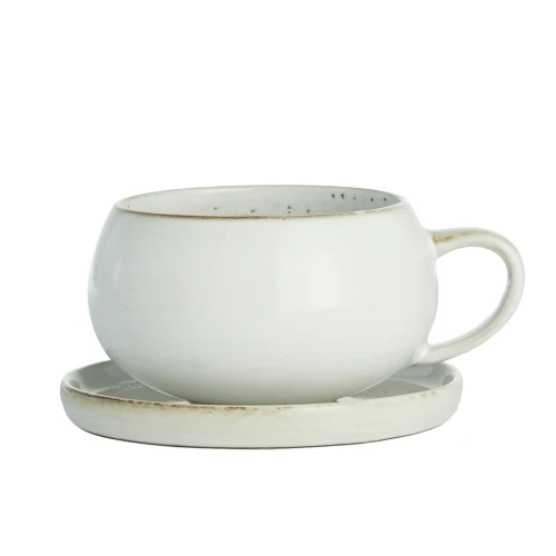 Biała ceramiczna filiżanka o zaokrąglonym kształcie, wys. 7,5 cm, stoi na spodku. Na krawędziach filiżanki i talerzyka widoczna ciemniejsza linia dekoracyjna. Ujęcie frontalne.