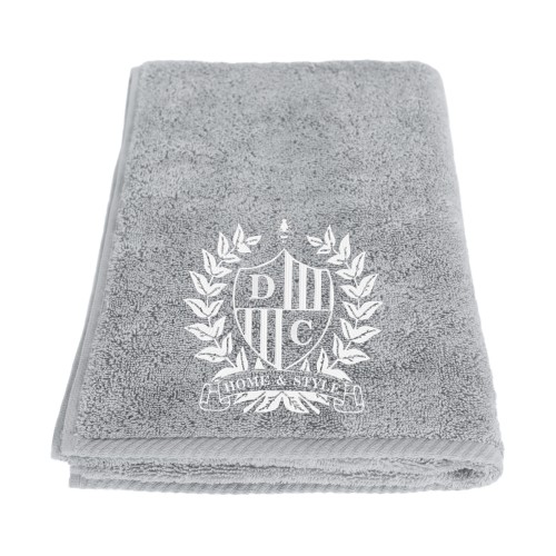 Personalizowany ręcznik w szarym kolorze z haftem. W widoku z boku, leżący, z widocznym logo i napisem HOME & STYLE. Wykonany z egipskiej bawełny, o gładkiej fakturze, dobrze wchłaniający wilgoć. Idealny do użytku domowego.
