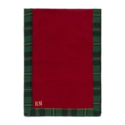 Bieżnik Tartan w kolorze czerwonym z zielonymi i żółtymi paskami. Widoczny haft z logo RM w prawym dolnym rogu. Ułożony na płasko, z prostym tłem, ukazującym jego wzór i detale. Idealny do dekoracji stołu.