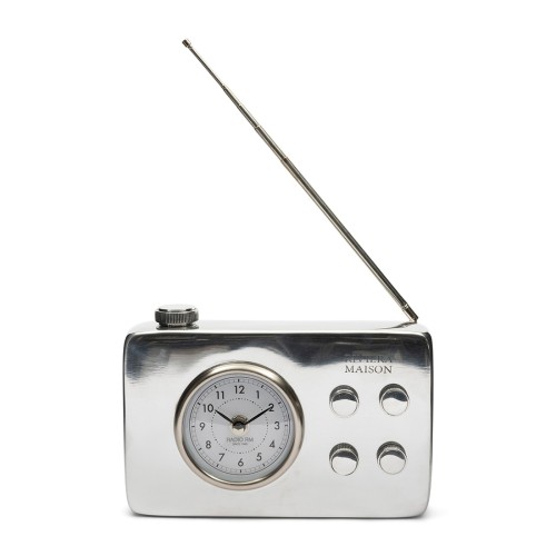 Zegar RM FM Radio Clock Riviera Maison w formie retro, metaliczny, z okrągłym zegarem w centralnej części, trzema przyciskami po prawej stronie i teleskopową anteną. Ułożony frontalnie na białym tle.