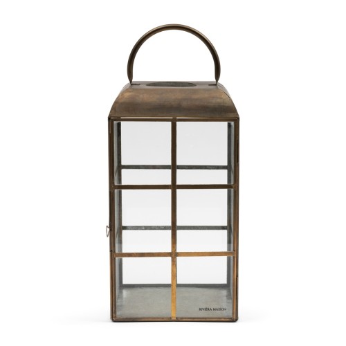 Latarnia Bastidonne Lantern M o wysokości 44 cm, w kształcie prostokąta, z metalową ramą w kolorze mosiądzu i szklanymi ściankami. Posiada uchwyt do przenoszenia, wewnątrz widoczna metalowa podstawa. Idealna do oświetlenia wnętrz i na zewnątrz.