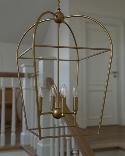 Złota lampa sufitowa Clue o geometrycznym kształcie z pięcioma źródłami światła. Wisi na łańcuchu w jasnym wnętrzu, z metalową konstrukcją i przezroczystymi kloszami. Idealna do nowoczesnych aranżacji.