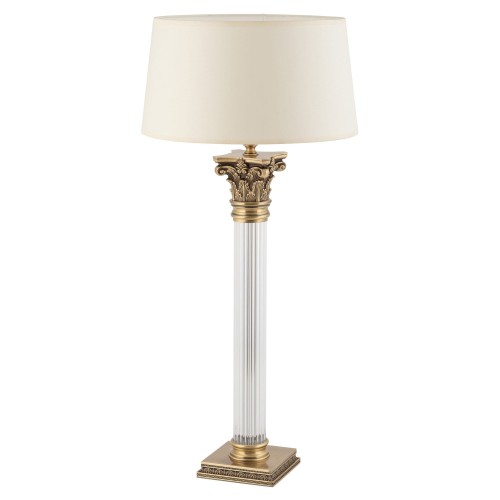 Lampa stołowa Vera z abażurem w kolorze kremowym, zdobioną złotą podstawą w stylu klasycznym. Wysokość 70 cm, szerokość 32 cm, głębokość 32 cm. Przezroczysta kolumna z detalami na górze, stojąca na kwadratowej podstawie.
