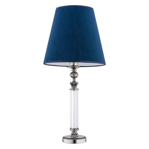 Lampa stołowa Merano o wymiarach 30x30x65 cm. Posiada niebieski, aksamitny klosz w kształcie stożka oraz elegancką, przezroczystą podstawę z metalowymi zdobieniami. Ujęcie z boku, stojąca na białym tle.