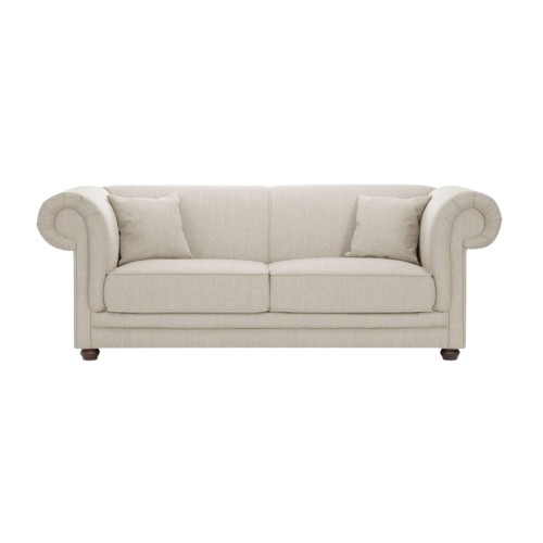 Trzyosobowa sofa Savero w jasnym, beżowym kolorze, o wymiarach 212x103x80 cm, z zaokrąglonymi podłokietnikami i dwiema poduszkami. Mebel stojący na ciemnych, drewnianych nogach, o prostym, eleganckim designie.