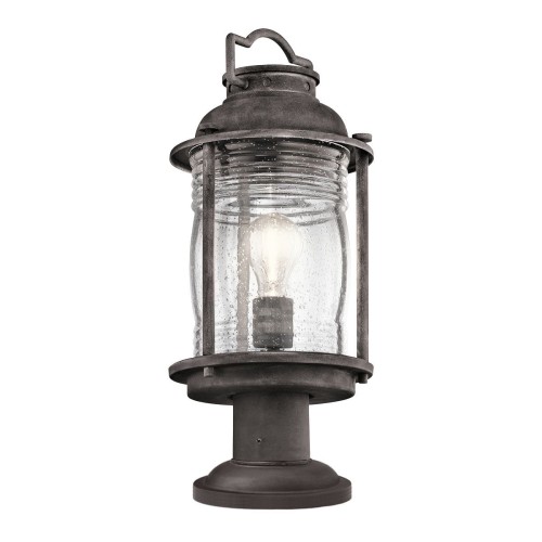 Lampa zewnętrzna stojąca Ashmore w kolorze cynkowym, o wymiarach 19,3x47 cm. Posiada szklany klosz z widoczną żarówką, osadzona na okrągłej podstawie. Stylizowana na latarnię, z dekoracyjnym uchwytem u góry. Idealna do ogrodu lub na taras.