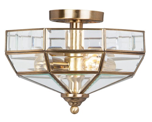 Plafon Elegance w kolorze antycznego mosiądzu o wymiarach 32x23 cm. Klosz z przezroczystego szkła o geometrycznym kształcie, z widocznymi detalami metalowymi oraz źródłem światła wewnątrz. Zainstalowany na suficie, idealny do eleganckich wnętrz.