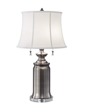 Lampa stołowa Wilington z niklowanym korpusem i białym abażurem o wysokości 69 cm. Kształt cylindryczny z dekoracyjnymi elementami, z dwoma zwisającymi uchwytami do włączania. Idealna do stylowych wnętrz.