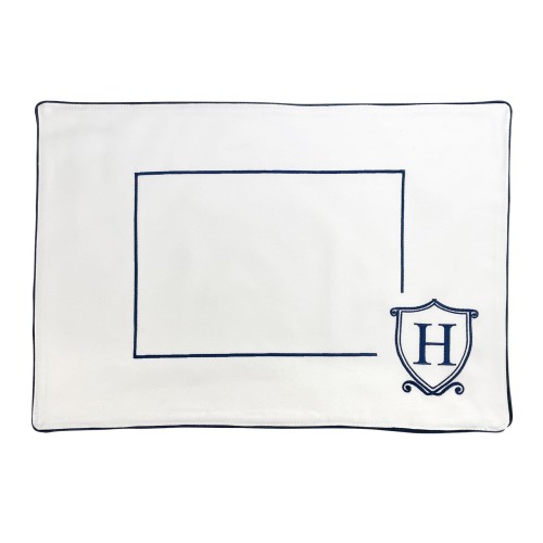Podkładka na stół Monogram Herb w kolorze białym z granatowym wykończeniem. Z przodu widoczny kontur prostokąta na wstawienie tekstu oraz logo „H” w tarczy. Produkt leży płasko na białym tle.
