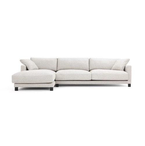 Jasnobeżowa narożna sofa z prostokątnym siedziskiem, poduszkami i chaise longue. Konstrukcja na czarnych nóżkach, tkanina o subtelnej fakturze, rozłożona do wypoczynku.