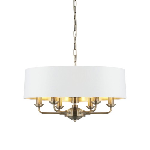 Lampa sufitowa wisząca Highclere z mosiądzu o okrągłej, białej tkaninowej osłonie i sześciu świecznikach. Wisi na łańcuchu, w ujęciu frontalnym, z widocznym detalem konstrukcji. Idealna do eleganckich wnętrz.