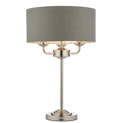 Lampa stołowa Highclere w kolorze szarym z niklowanym podstawą, o wysokości 50 cm. Klasyczny kształt z okrągłym kloszem i trzema ramionami. Ujęcie frontalne, stojąca na płaskiej powierzchni na jasnym tle. Idealna do nowoczesnych wnętrz.