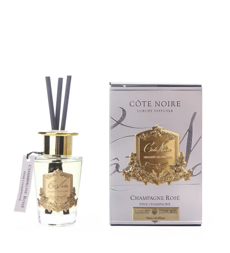 Dyfuzor Cote Pink Champagne 90 ml w szklanej butelce z złotą pokrywką i trzema czarnymi patyczkami, obok srebrne opakowanie z logo i napisem Champagne Rosé, na prostym tle.