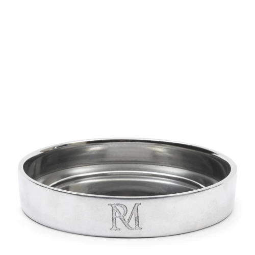 Srebrna, okrągła podstawka na świece Maxime Riviera Maison z metalicznym połyskiem i wytłoczonym napisem „RM” na boku. Zdjęcie pod kątem, na białym tle kontrastującym z powierzchnią.
