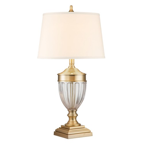 Lampa stołowa Dennison z solidnym podstawą w szczotkowanym mosiądzu, o zaokrąglonym kształcie oraz przezroczystym kloszu. Wysoka, z tekstylnym, białym abażurem, podświetla elegancko każde wnętrze. Ujęcie frontalne, na jednolitym tle.