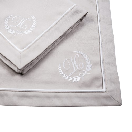 Personalizowana serwetka z haftem monogram, 40x40 cm, w kolorze jasnoszarym. Złożona, z widocznym haftem w odcieniach bieli oraz elegancką lamówką. Ujęcie frontalne na gładkim tle, bez dodatkowych elementów w otoczeniu.