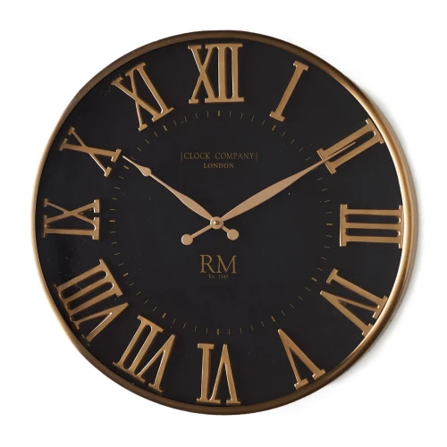 Zegar ścienny London Company Riviera Maison, średnica 51 cm. Czarne tło z dużymi złotymi cyframi rzymskimi. Złota ramka, minimalistyczny design. Wskazówki w złotym kolorze. Produkt wiszący, widoczny z przodu na jasnym tle.