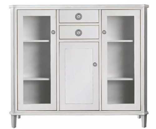 Witryna drewniana Henshaw Laura Ashley, jasnoszara, o wymiarach 128x42x116 cm. Posiada dwie przeszklone szafki boczne, centralną szufladę oraz zamykaną szafkę. Wykończona subtelnym zdobieniem, na lekko wysmuklonych nogach.