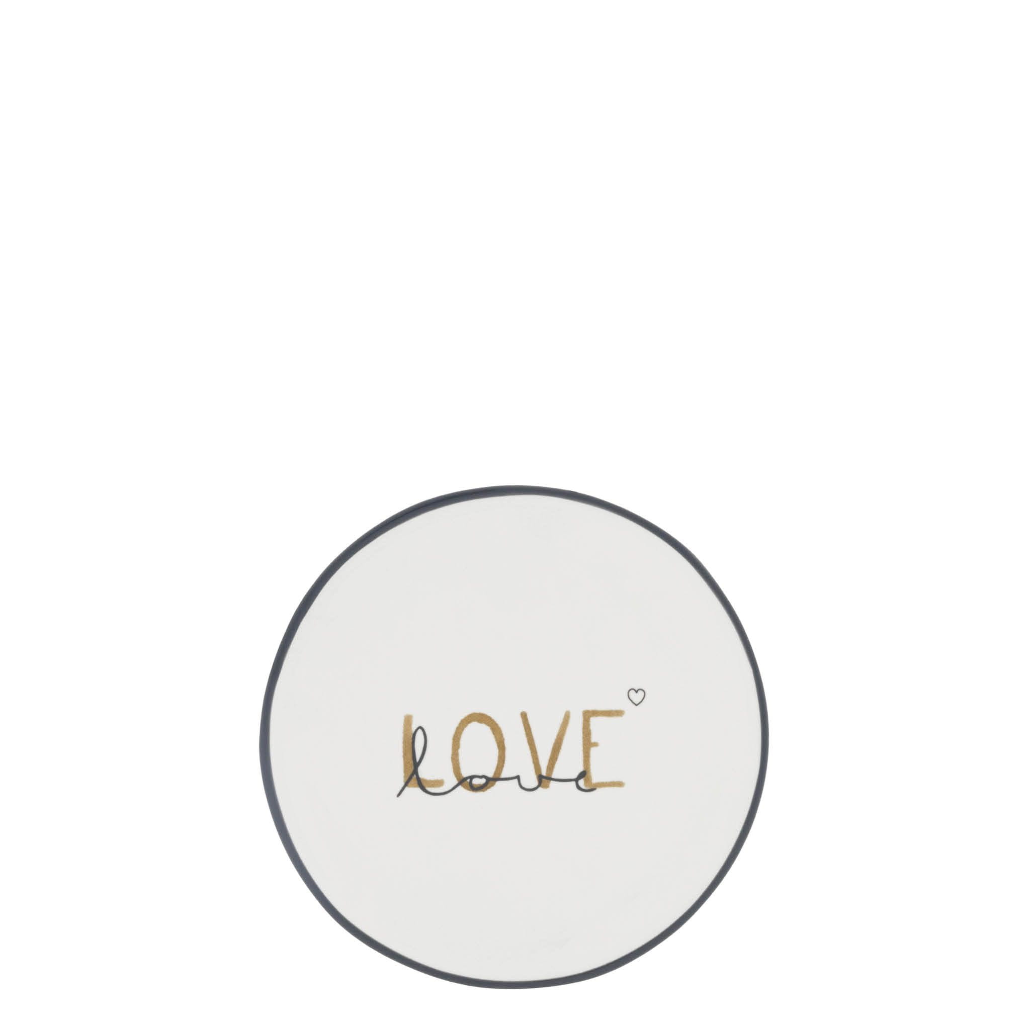 Talerzyk Podstawka Double Love Bastion Collection w kolorze białym z dekoracją love w odcieniach złota i czerni. Okrągły kształt, z delikatną, ciemną obwódką. Produkt leżący na białym tle, bez dodatkowych akcesoriów w otoczeniu.