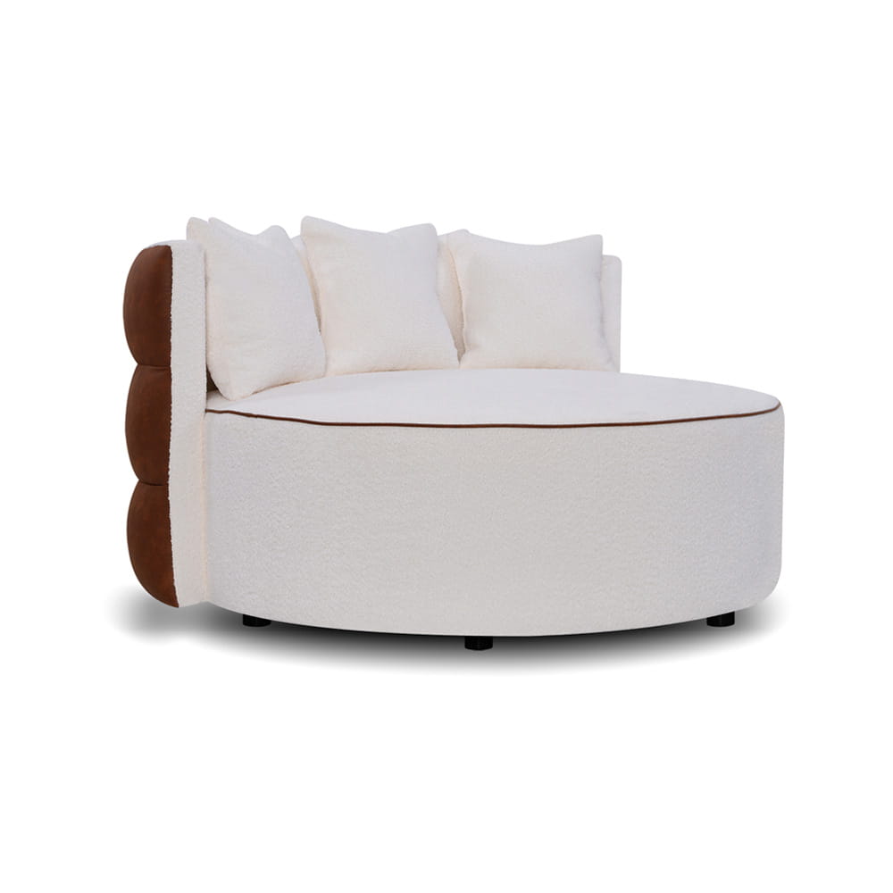 Półokrągła sofa w kolorze kremowym z brązowym akcentem, wykończona miękkim materiałem. W zestawie trzy poduszki, zaokrąglona forma. Ujęcie frontalne, produkt stoi na niskich nóżkach. Idealna do nowoczesnych wnętrz. Wymiary: 132x132x69cm.