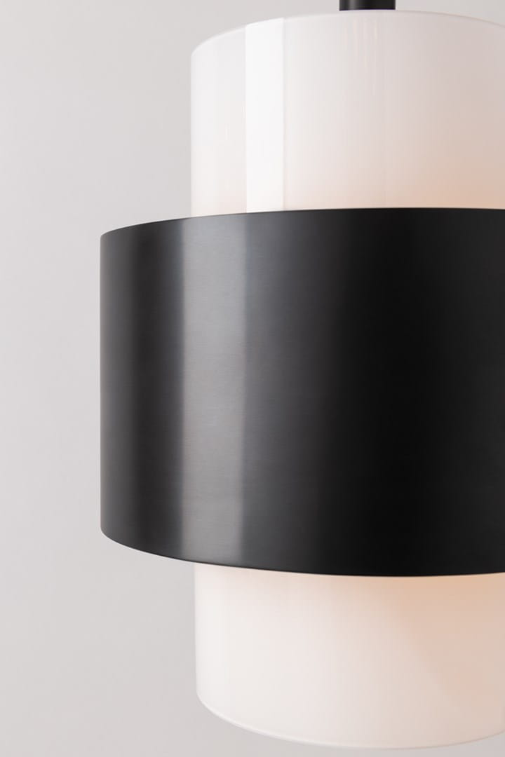 Elegancka lampa sufitowa Corinth M o okrągłym, białym ekranie i matowej, czarnej obręczy. Ujęcie z boku, ukazujące połączenie kolorów oraz gładkie wykończenie. Produkt wiszący, doskonale pasujący do nowoczesnych aranżacji wnętrz.