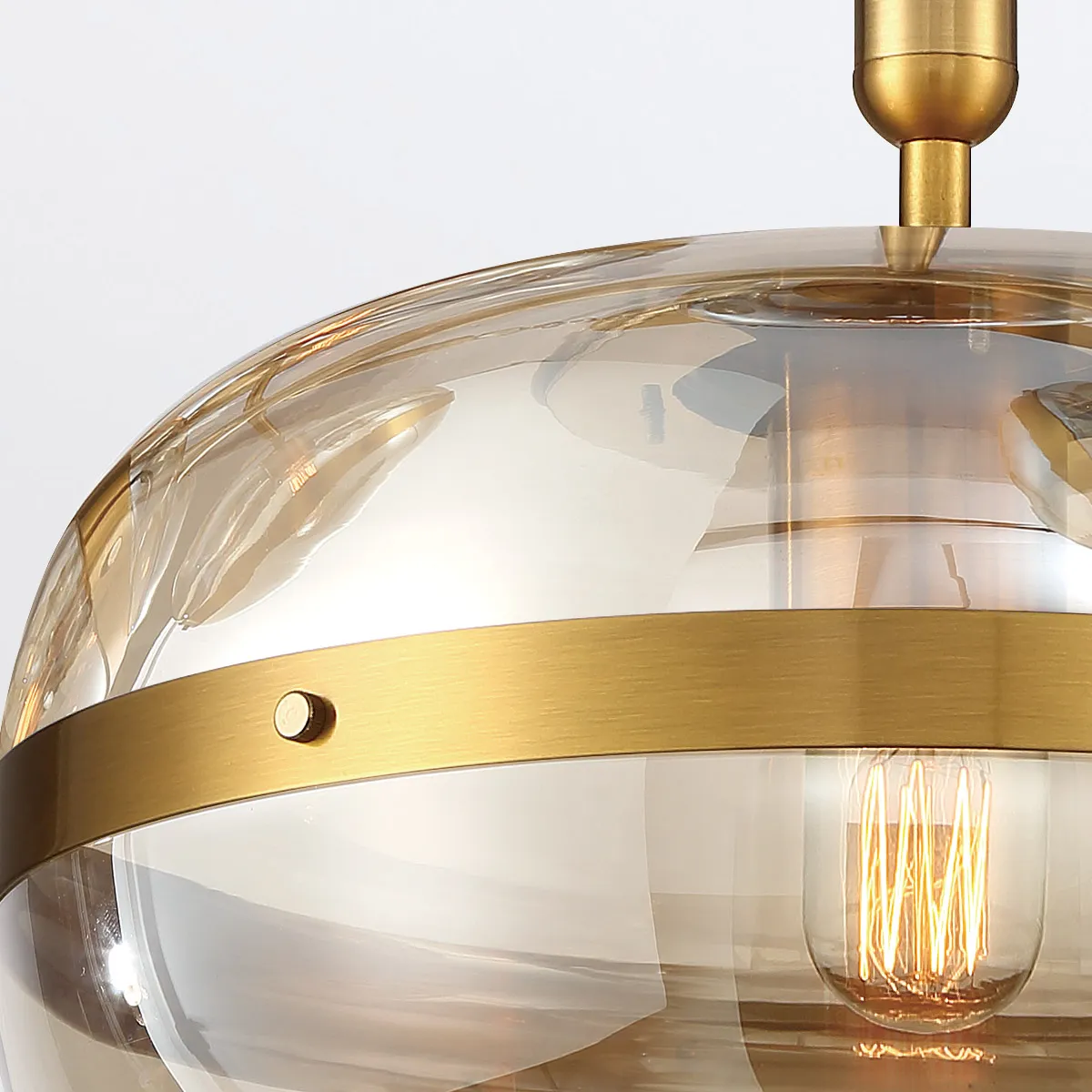 Designerska lampa wisząca Nottingham w kolorze mosiądzu, z przezroczystym kloszem. Kąt ujęcia z góry, ukazujący detale mocowania i żarówki. Produkt wiszący, idealny do nowoczesnych aranżacji wnętrz.