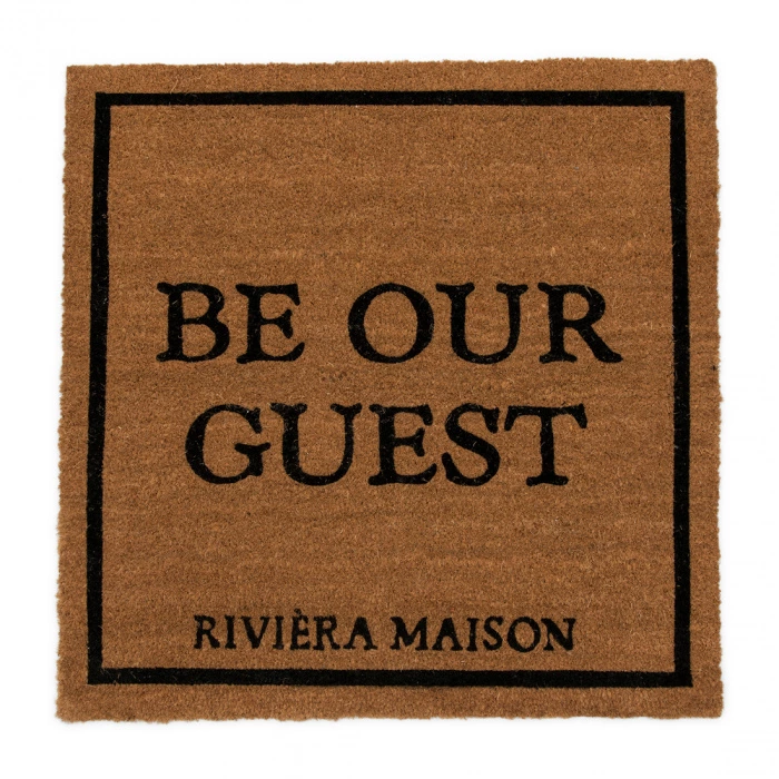 Wycieraczka Be Our Guest Riviera Maison w kolorze brązowym o wymiarach 80x80 cm, wykonana z włókna kokosowego. Na powierzchni widoczny czarny napis BE OUR GUEST oraz logo RIVIÈRA MAISON. Produkt leży płasko na jednolitym tle.