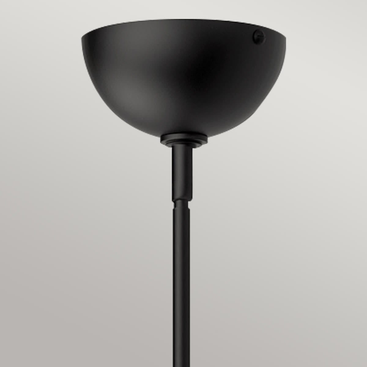 Czarna lampa wisząca Jude o półkulistym kształcie, wykonana z matowego metalu, zawieszona na smukłym, czarnym przewodzie. Ujęcie z dołu, ukazujące górną część lampy i mocowanie. Proste tło w jasnym kolorze podkreśla produkt.
