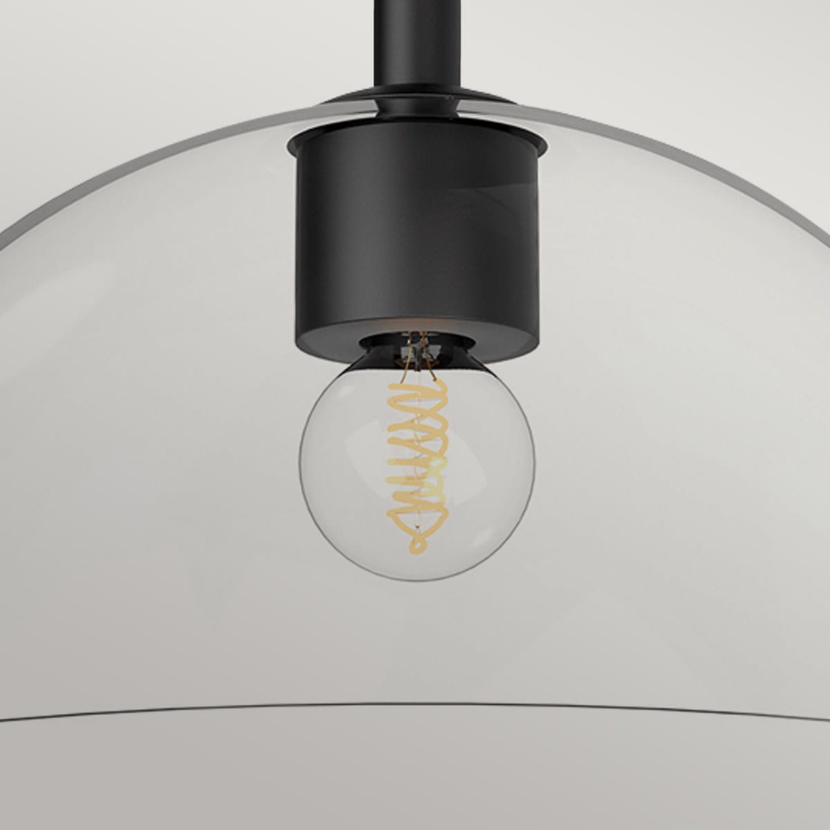 Stylowy plafon Jude w kolorze czarnym z przezroczystym kloszem w kształcie półkuli. Widoczna żarówka z spiralnym włóknem wewnątrz. Produkt wiszący, uchwycony z dołu, w minimalistycznym otoczeniu na jasnym tle.