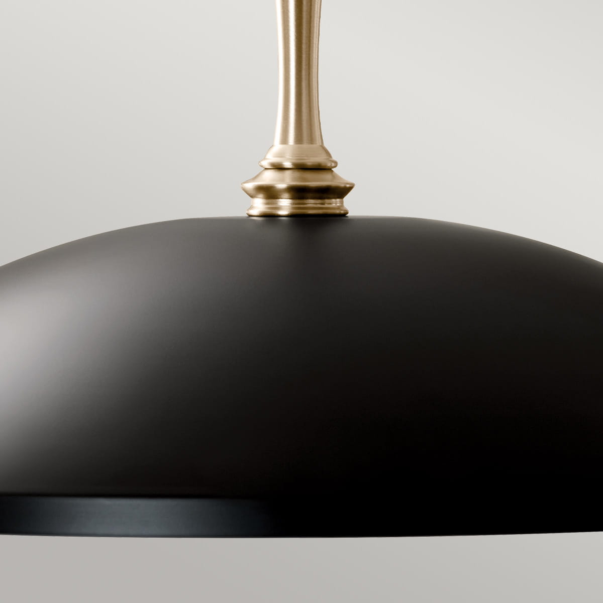 Nowoczesna lampa Delarosa z matowym, czarnym kloszem i dekoracyjnym, złotym mocowaniem. Ujęcie z góry, pokazujące gładką powierzchnię oraz szczegóły przymocowania. Produkt zawieszony, idealny do minimalistycznych wnętrz.