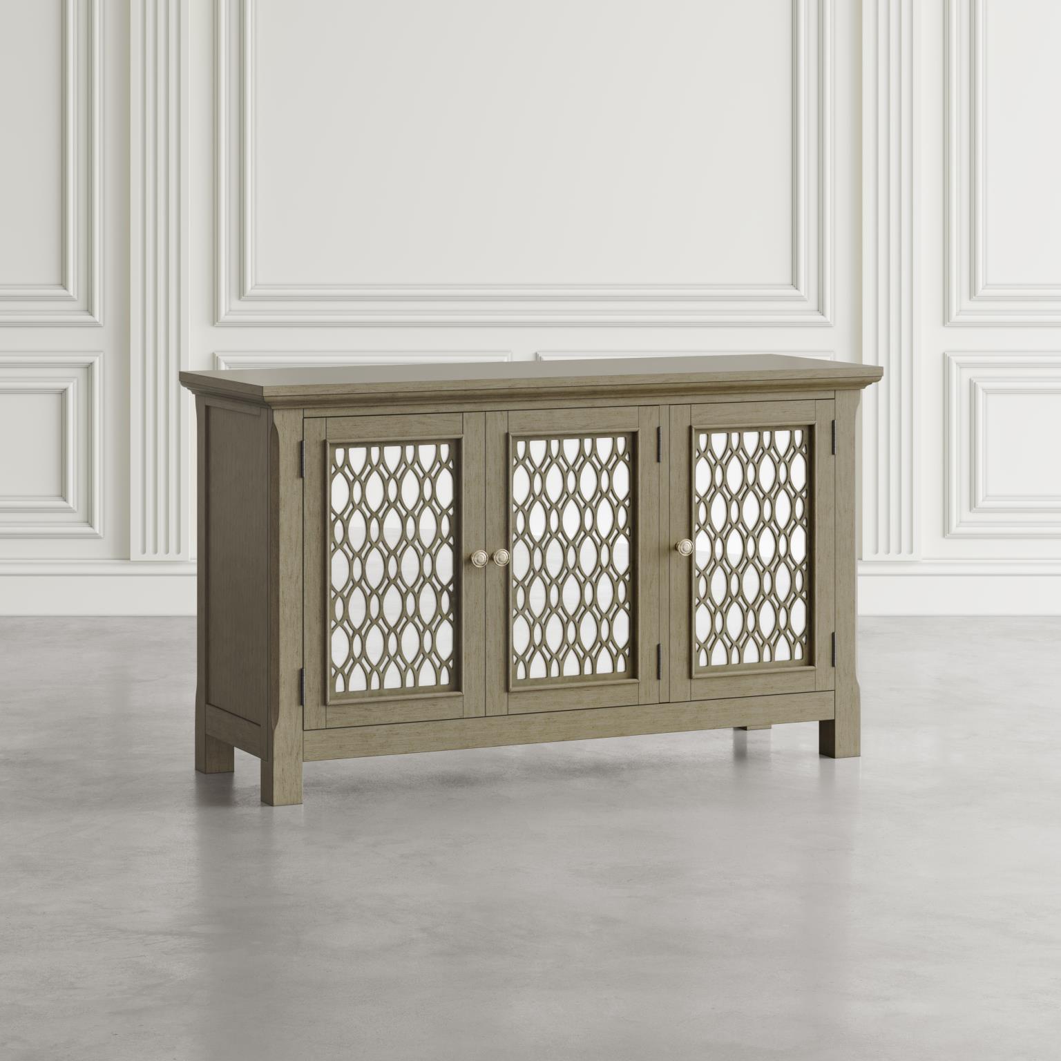 Komoda Avola Złota 137cm w kolorze jasnego drewna z trzema przeszklonymi drzwiczkami, ozdobnymi detalami w formie cienkich, złotych lampek. Ujęcie frontalne, produkt stojący na podłodze w minimalistycznym wnętrzu z białymi ścianami.