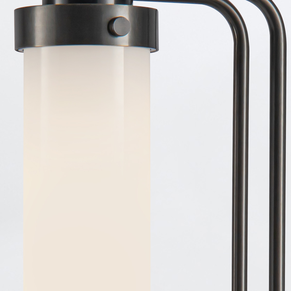 Lampa stołowa Wynwood w kolorze brązowym z metalową podstawą i cylindrycznym, mlecznym kloszem. Ujęcie zbliżeniowe, pokazujące detale mocowania oraz fakturę klosza. Proste, jasne tło podkreśla produkt.