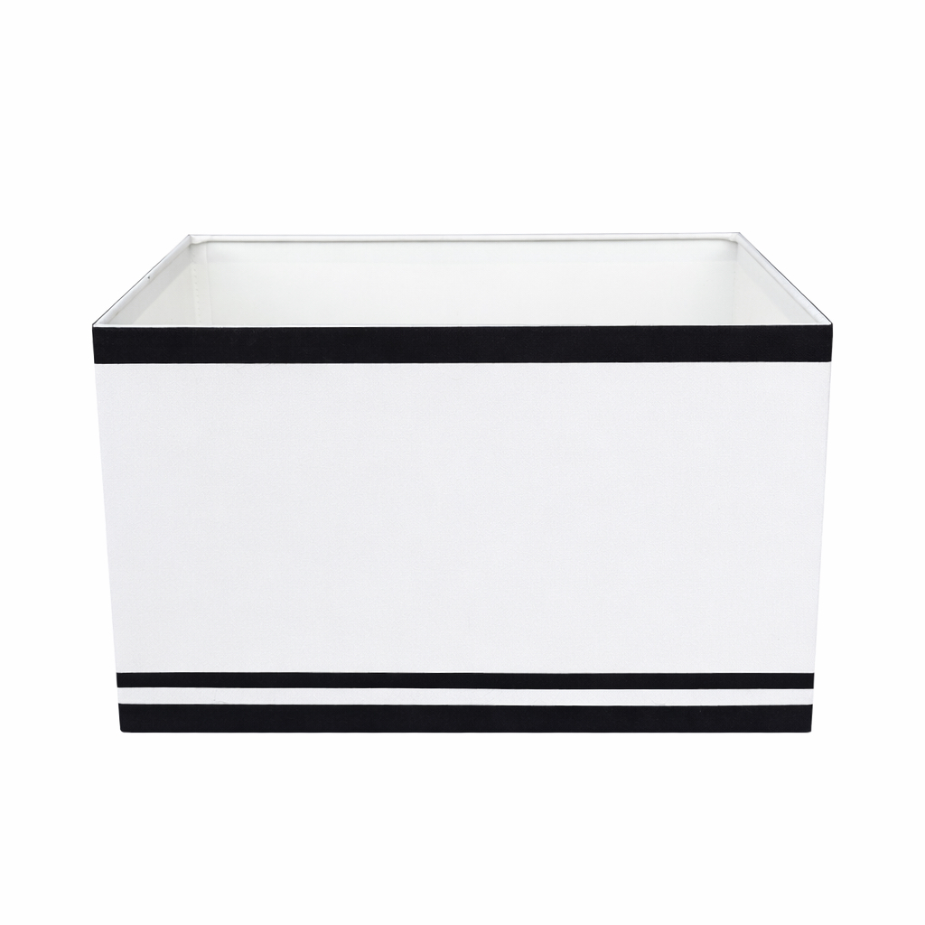 Prostokątny abażur Riviera w kolorze biało-czarnym o wymiarach 30x20x20 cm. Produkt z materiału, z czarnymi paskami na górnej i dolnej krawędzi, umieszczony w pozycji leżącej, z widocznym wnętrzem w kolorze białym.
