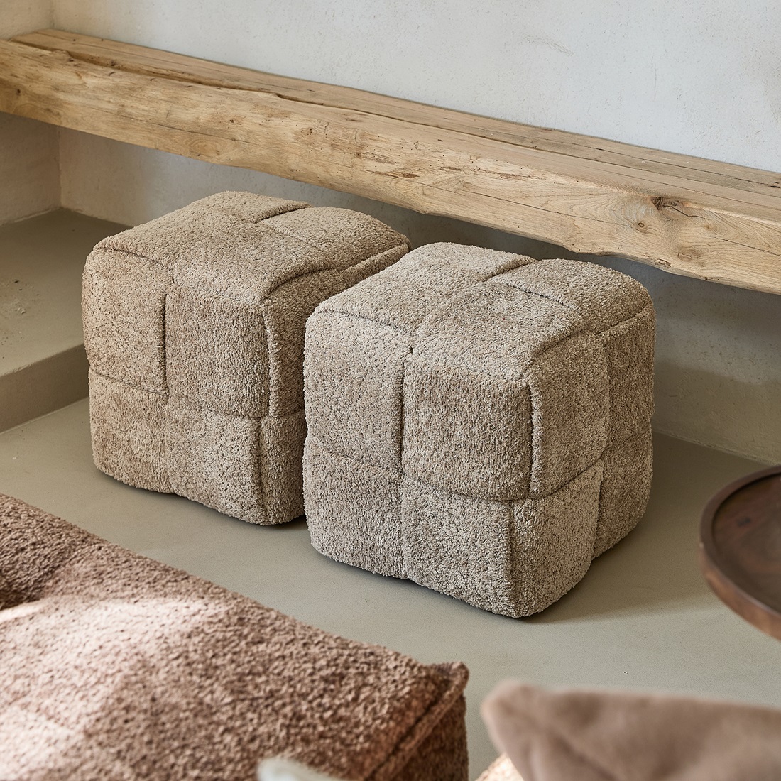 Puf Qbic Stool w kolorze soft walnut, o wymiarach 40x45 cm, wykonany z teksturowanej tkaniny. Produkt ma kształt sześcianu, z widocznymi przeszyciami tworzącymi kwadratowe segmenty. Dwa pufy ustawione obok siebie na neutralnym tle.