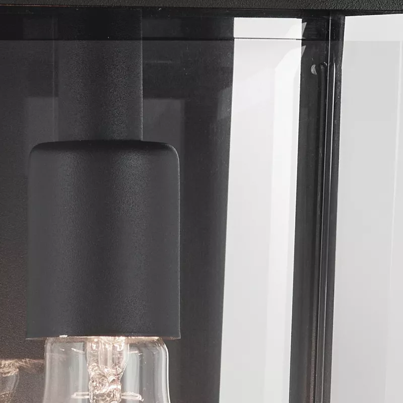 Kinkiet zewnętrzny Mathus M w kolorze czarnym, z metalowym kloszem i przezroczystym szkłem. Widoczne gniazdo na żarówkę oraz górna część lampy. Produkt w zbliżeniu, ukazujący detale wykończenia.