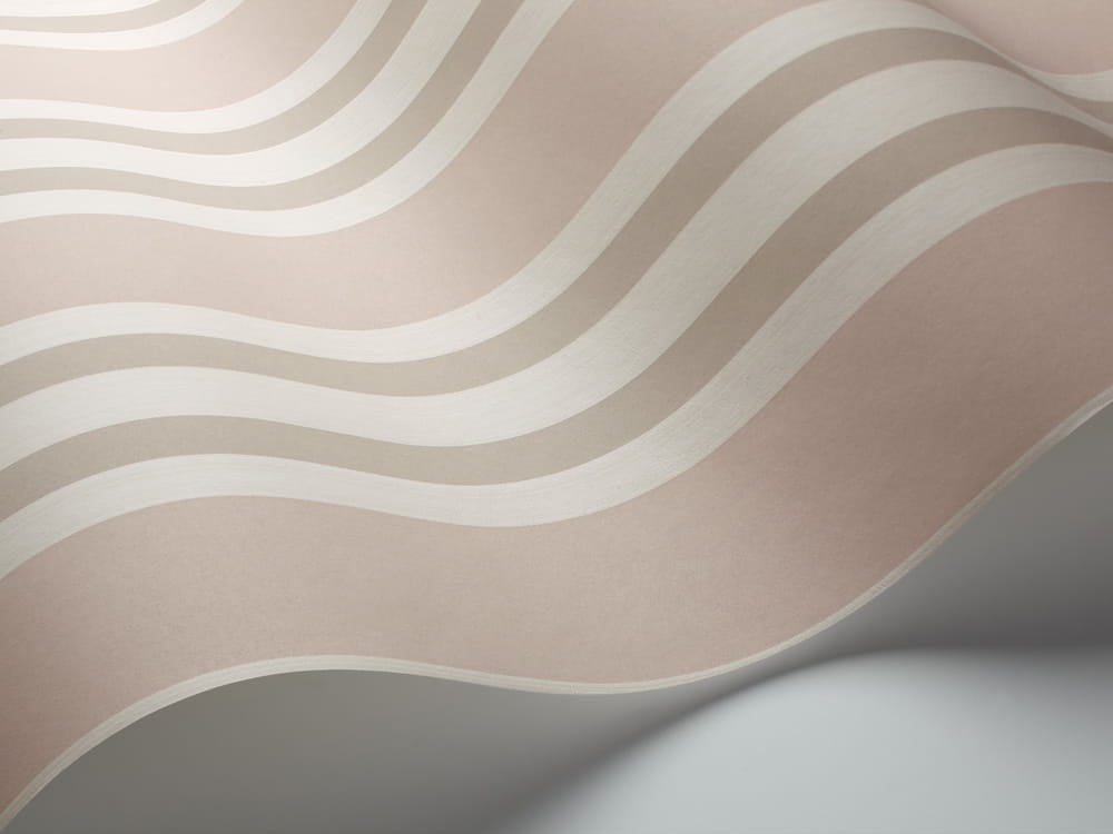 Tapeta Cole and Son Polo Stripe w odcieniach bieli, różu i beżu, z falistym wzorem. Ujęcie z boku ukazuje jej teksturę i delikatny połysk. Produkt prezentowany na gładkiej powierzchni, podkreślający elegancję oraz subtelność kolorystyki.