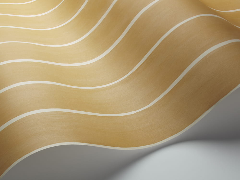 Tapeta Cole and Son Marquee Stripe White/Mustard w kolorze musztardowym z falującym wzorem w białe pasy. Produkt leży luźno, ukazując teksturę materiału oraz delikatny połysk. Tło jasne, co podkreśla detale wzoru.