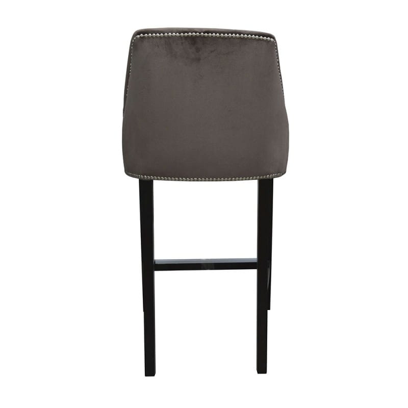 Hoker tapicerowany typu Chesterfield o szarym, aksamitnym obiciu, z delikatnym, kontrastującym przeszyciem. Ujęcie z tyłu, podkreślające prostą, elegancką formę oraz czarne, drewniane nogi. Produkt nadaje się do nowoczesnych wnętrz.