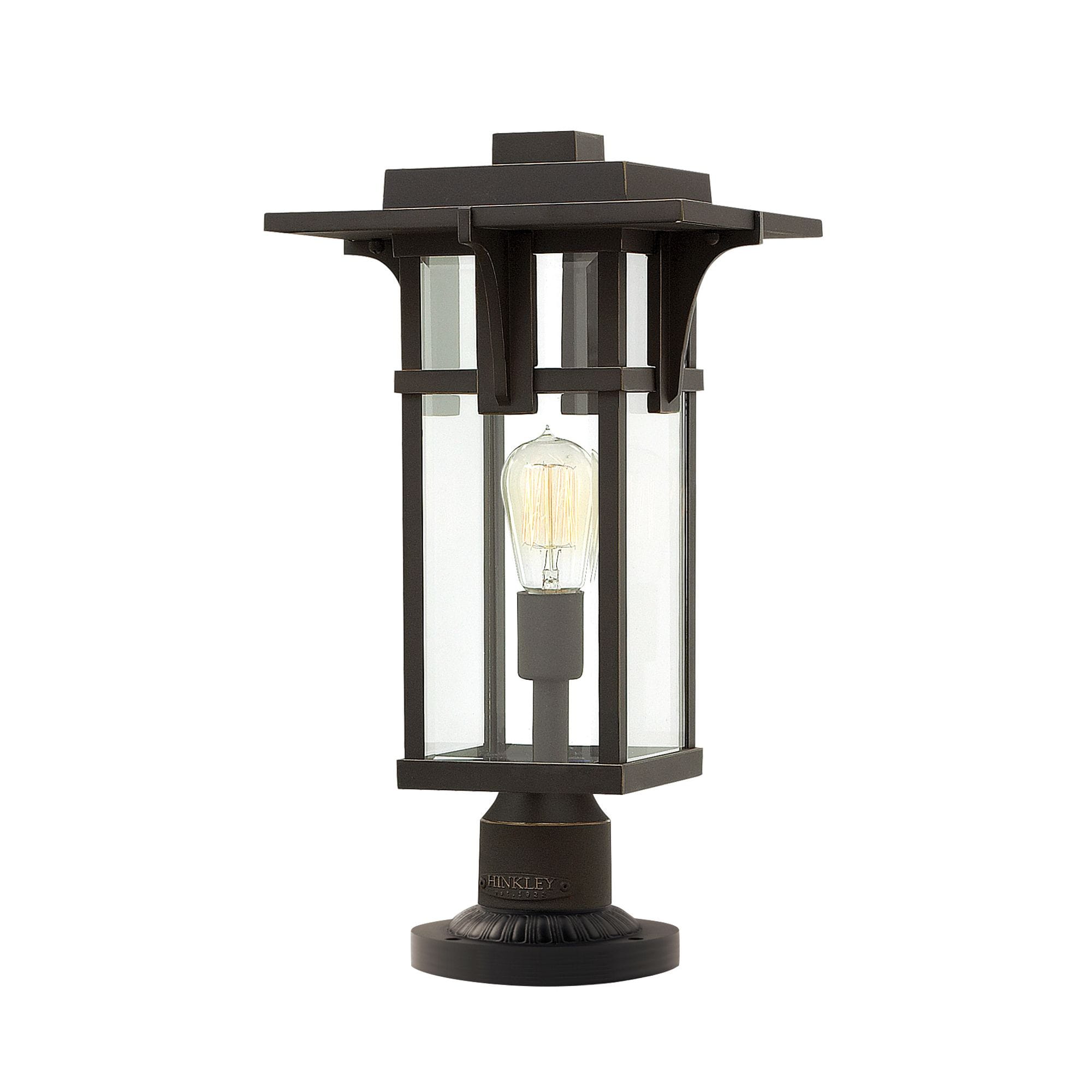 Stojąca lampa zewnętrzna Traino w kolorze brązowym, o wymiarach 23,5x49 cm, z szklanym kloszem i widoczną żarówką. Produkt ma prostokątną podstawę oraz ozdobne detale na górze. Idealna do oświetlenia przestrzeni na zewnątrz.